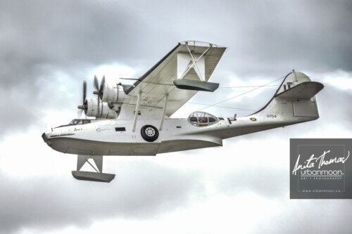 Aviation photography - Consolidated PBY-5A Canso, manufactured in 1944, by Canadian Vickers in Montreal and served with the RCAF until 1961. This is a flying version, part of a larger collections of war planes at the Canadian Warplane Heritage Museum in Hamilton, Ontario, Canada. It is an amphibious aircraft and I am told by one veteran that one pilot radioed in during the war to land at a particular airport. He was told "You can't land here!" The pilot responded "Can so!" as his wheels deployed out from the sides of its body. It is said that this is how the PBY-5A got its nickname, the Canso. You can see the wheels in its side in this photo. When it lands on water, wingtip stabilizing floats drop down.
© Anita Thomas - Urbanmoon. All Rights Reserved. consolidated canso
